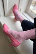 Pink high heels and socks on a white surface