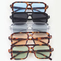 Stack of sunglasses with different frame designs and lens colors on a white background