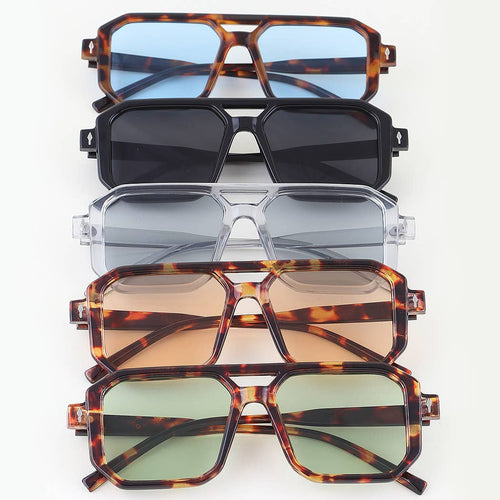 Stack of sunglasses with different frame designs and lens colors on a white background