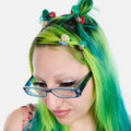 Person with green and blue hair styled in pigtails with decorative clips against a white background
