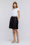 Woman wearing a black skirt with white top on a plain background