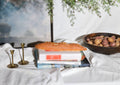 Decorative scene with books, a loaf of bread, and a plant on a white surface.