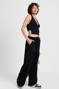 Person wearing a black sleeveless top and wide-leg pants on a white background