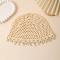 Beige knitted hat with pearl embellishments on a beige background