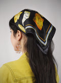 Person wearing a decorative headscarf with a classical painting design on a plain background.