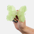 Hand holding a light green butterfly hair clip against a white background