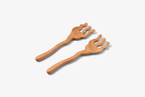 Two wooden serving spoons with a wavy design, lying on a white surface.
