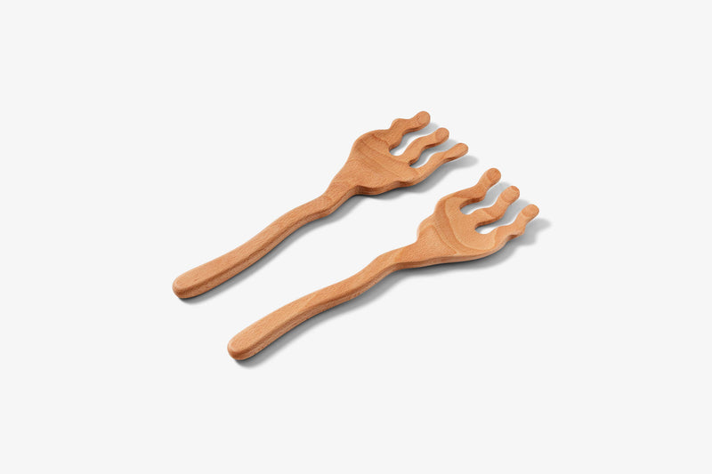 Two wooden serving spoons with a wavy design, lying on a white surface.